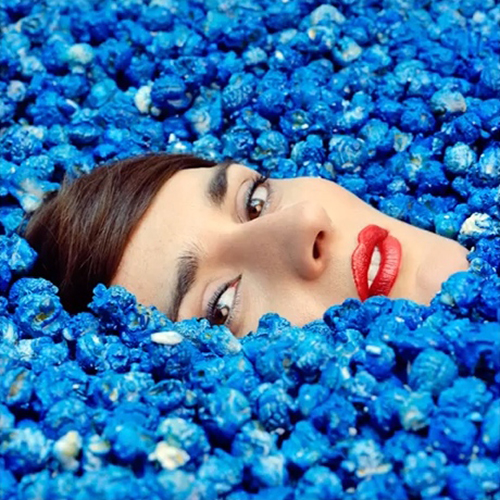 Yelle's head poking out of a sea of blue flowers Single Review: Yelle ‘Bouquet Final’
