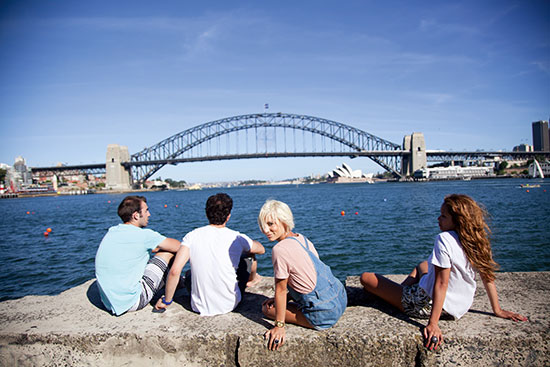 Sydney Harbour Bridge, Australia group of friends sitting by sydney harbour bridge