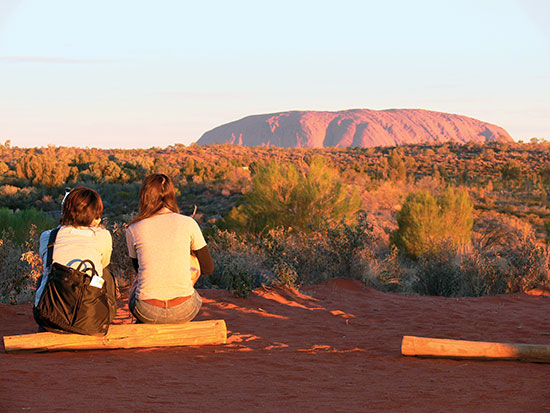 TBW-Contiki-Uluru two girls sitting in front of uluru