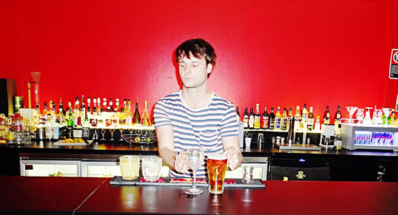 man pouring drinks behind a bar