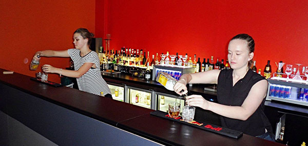 two girls making cocktails behind a bar