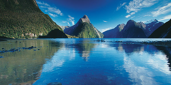 water reflecting the mountains in milford sound new zealand