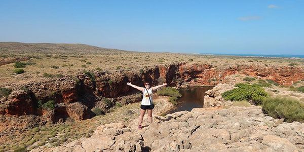 outback-camp-tours-arms-out girl standing on top of river cliff edge