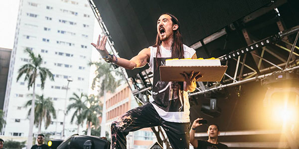 dj steve aoki holding a cake on stage
