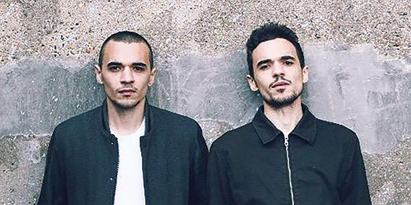 two men standing against a wall