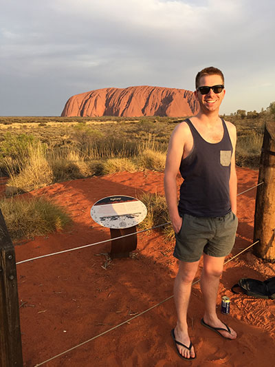 man standing in front of uluru australia