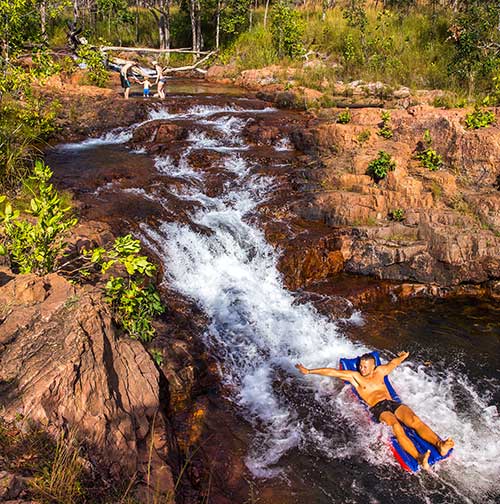 man sliding down the waterfall in kakadu australia