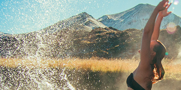 girl splashing in lake with mountain background