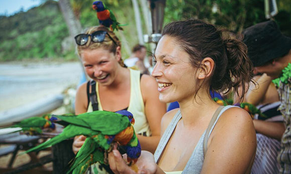 girls holding parrots on holiday