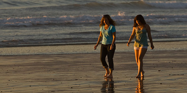 women-walking-on-the-beach two women walking on the beach barefeoot