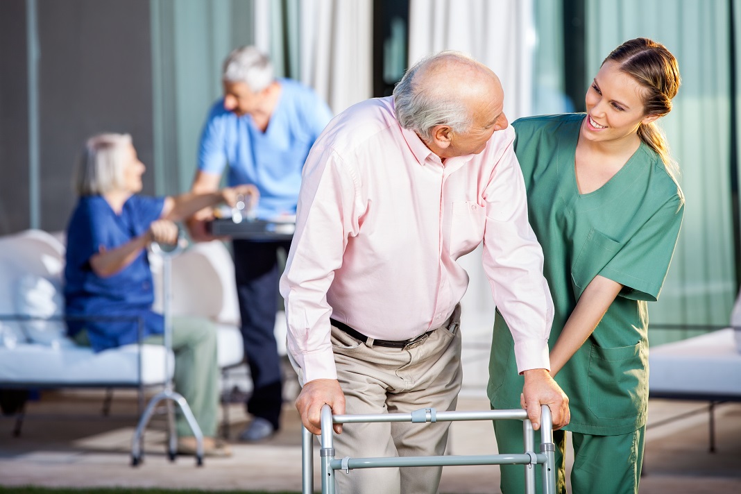 Happy Caretaker Assisting Senior Man In Using Zimmer Frame Nursing Jobs in Regional Western Australia